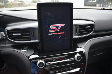 A close up photo of the center console of a car, with a tall screen.